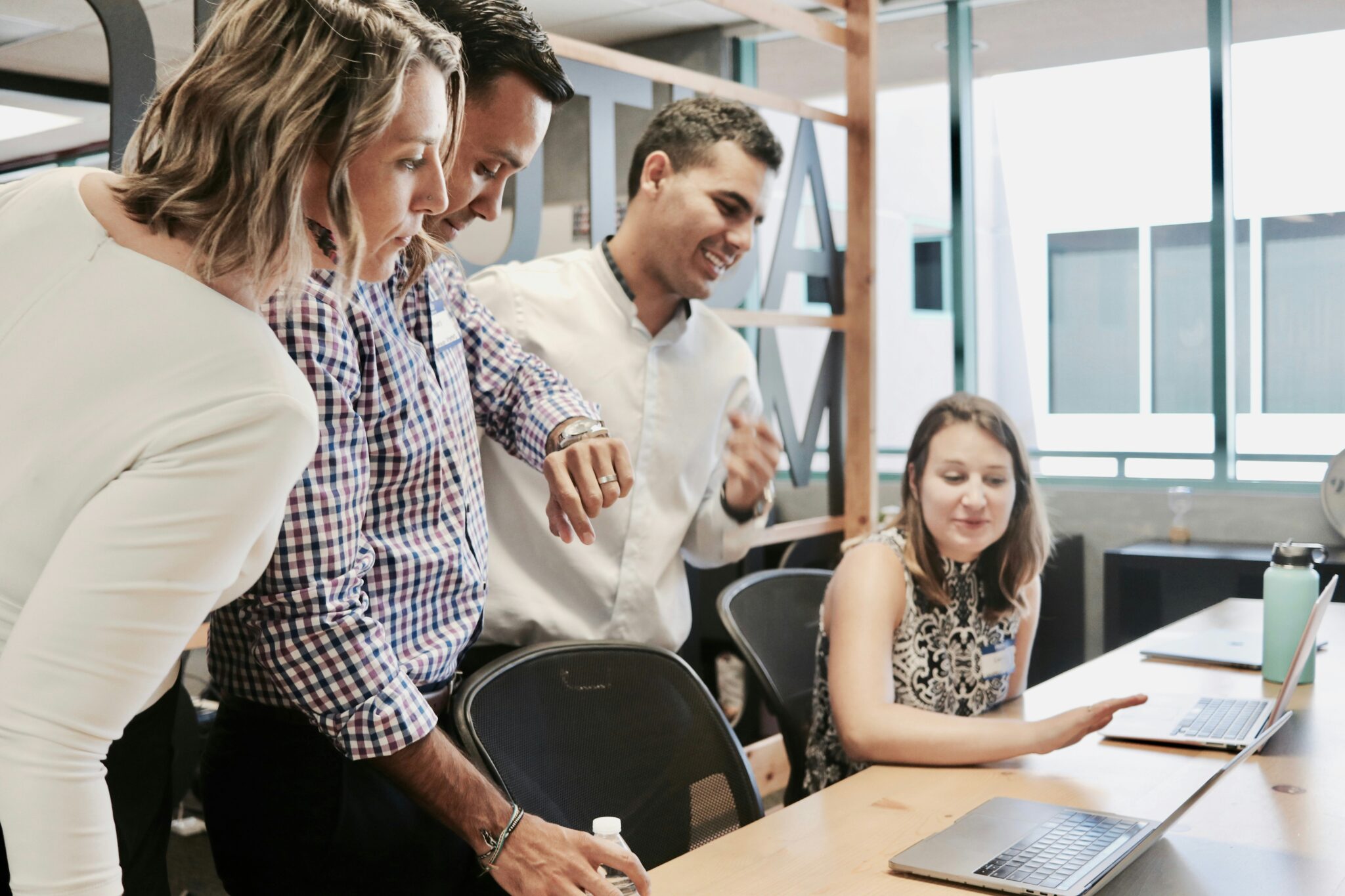 phot of coworkers interacting around laptops in an office